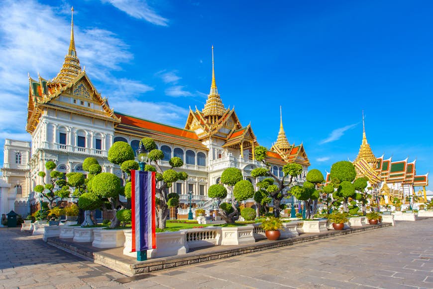 The golden stupa of the Grand palace, Wat Phra Kaew shimmers against a blue sky in Bangkok, Thailand.