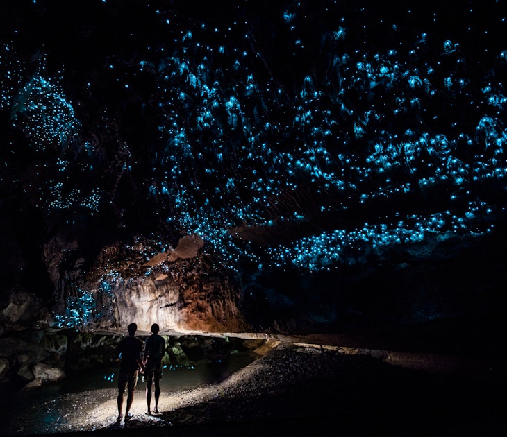 Two people explore the glowworm cathedral at the end of Waipu Cave in New Zealand.