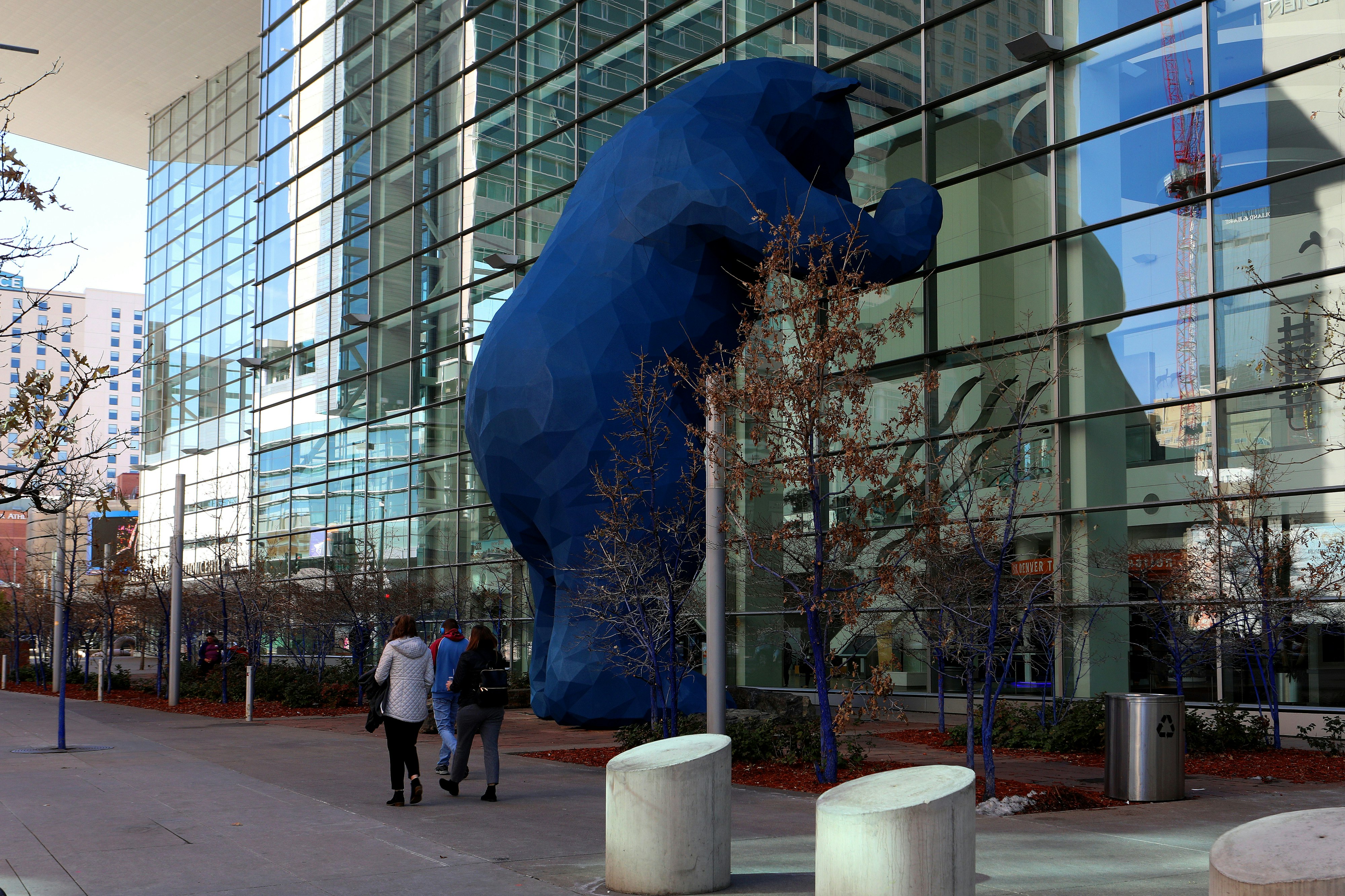 A sculpture of a giant blue bear peering into a building in Denver