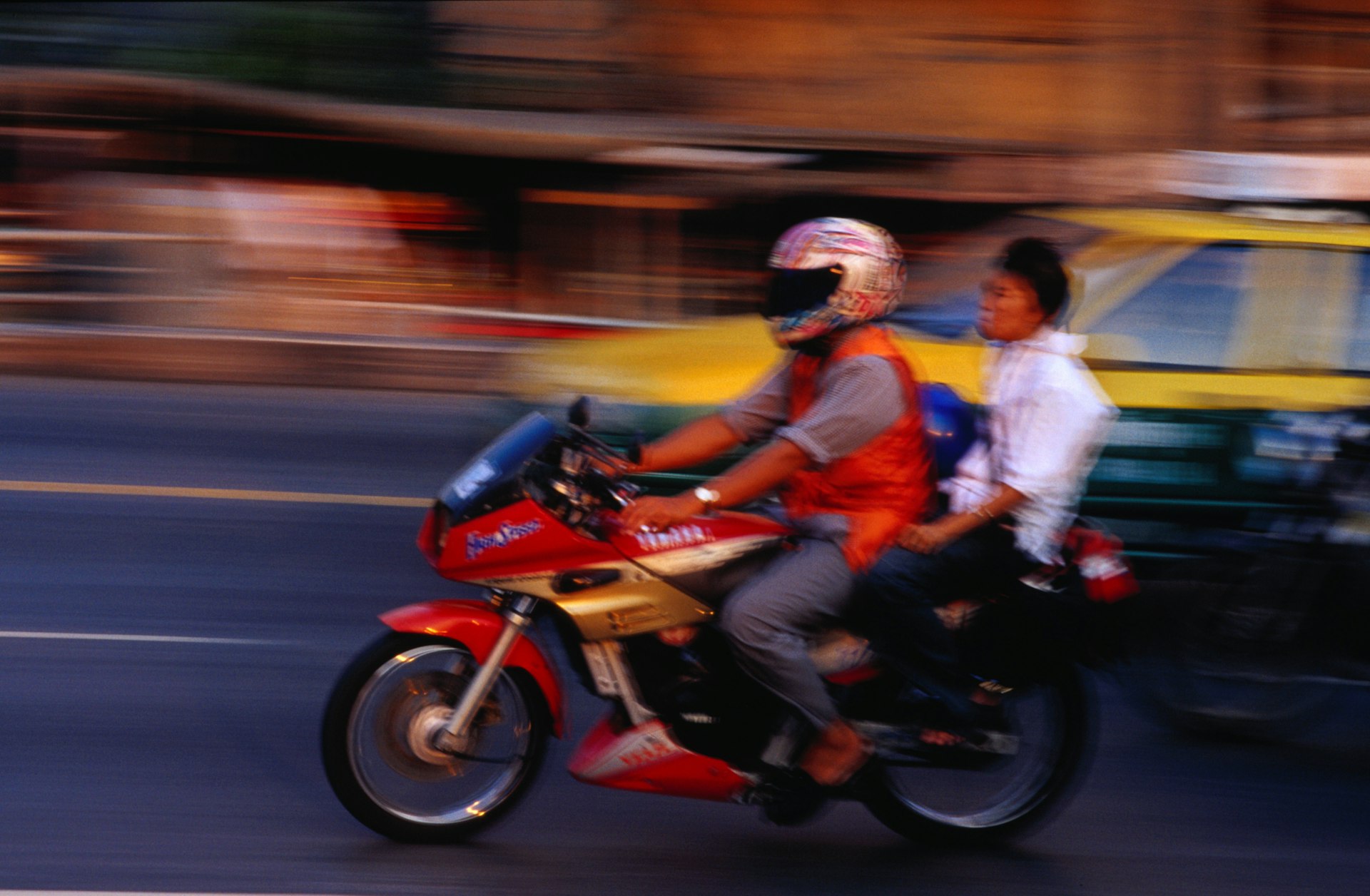 A motorcycle with a passenger flashes past in a blur on Th Ratchaprarop in Bangkok, Thailand.