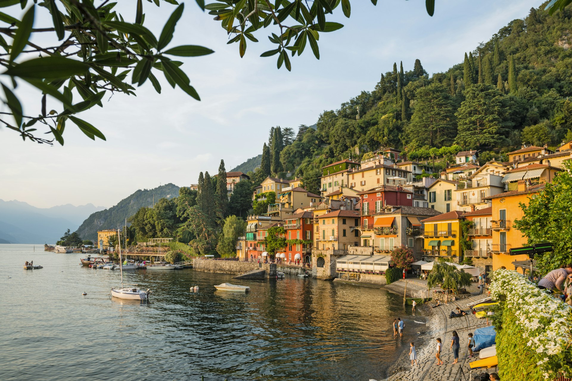 The village of Varenna on the shores of Lake Como. The village has many colourful buildings right by the water's edge, and is backed by dense green forest.