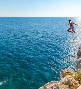 A boy is jumping from the cliff. Holidays in Montenegro; Shutterstock ID 634103288; your: Ben N Buckner; gl: 65050; netsuite: Client Services; full: Montenegro