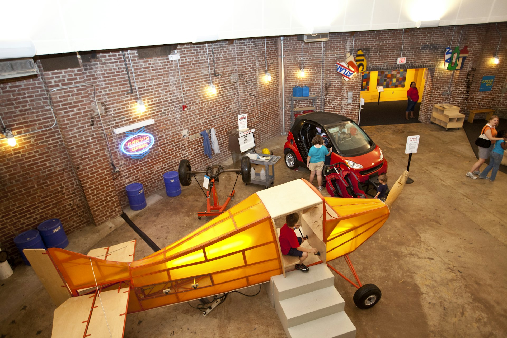 A little boy sits in a life size toy airplane while other children play with a small car at the Children's Museum of Pittsburgh