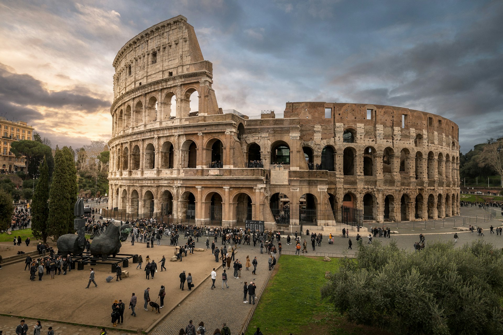 A huge ancient amphitheatre with crowds of people in front of it