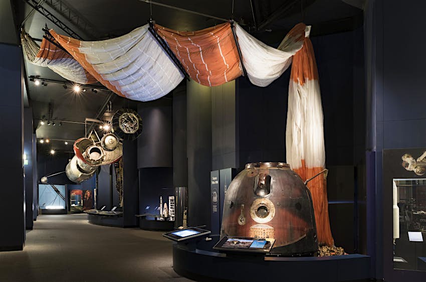 Soyuz Spacecraft in the Exploring Space Gallery Tim Peake's Soyuz Spacecraft, a metallic capsule just big enough to hold three people, with a red-and-white parachute arranged up the wall and over the ceiling