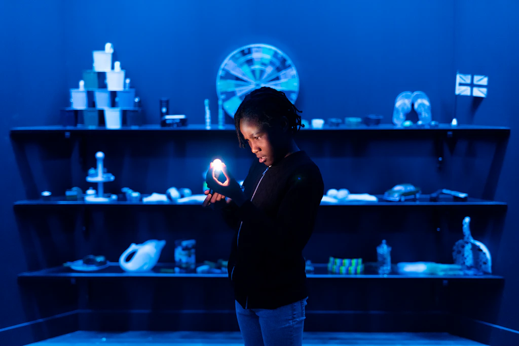 A child holds a small light in a room lit up in blue 