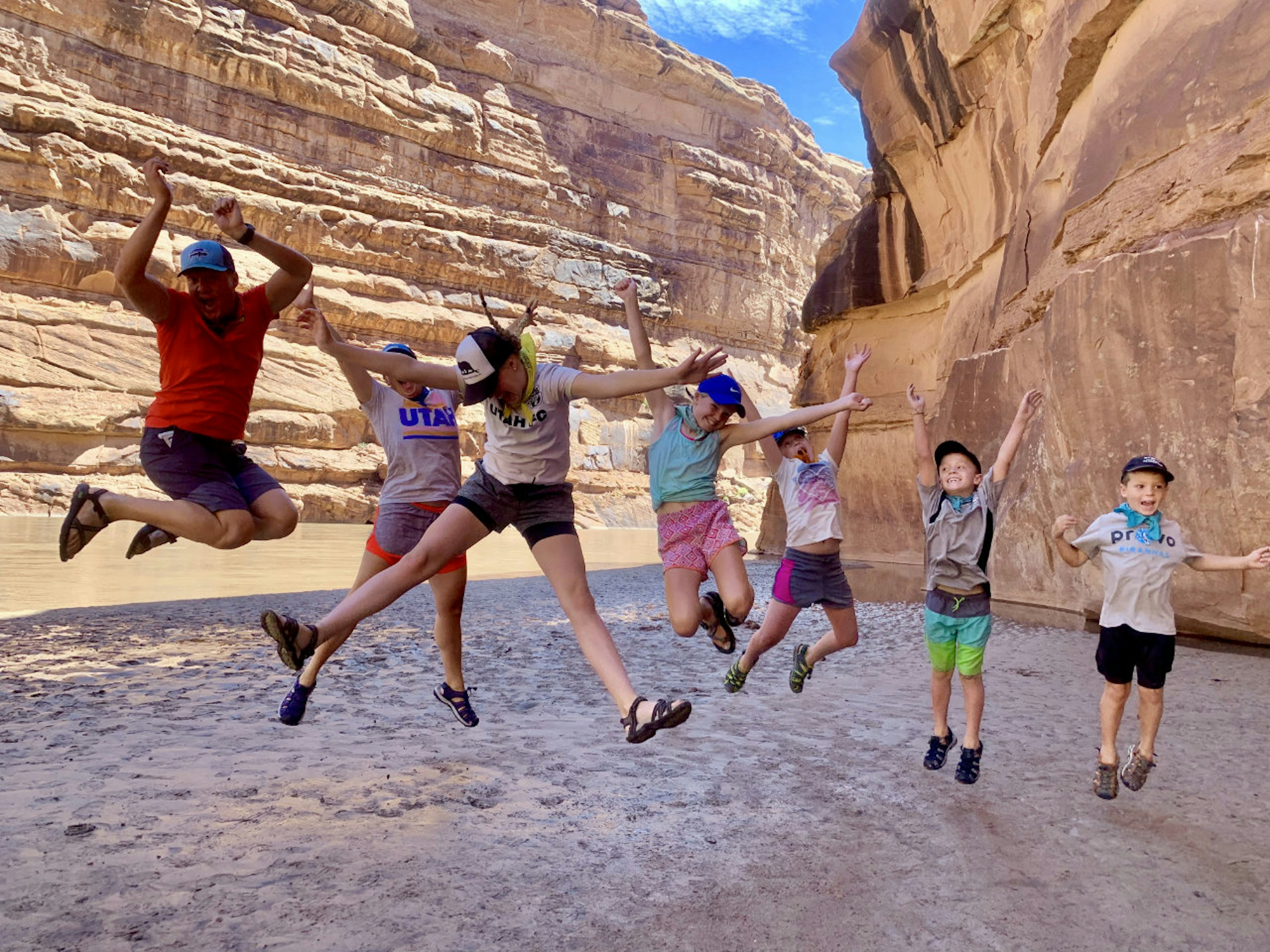 A family jumps on the banks of a canyon river