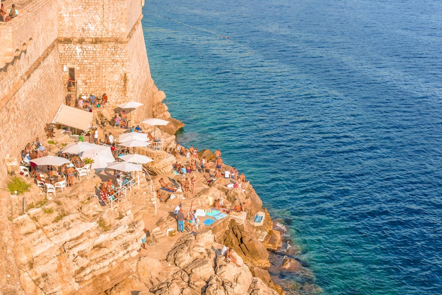 High-angle view of people sitting on the rocks at Buza bar, which is located outside of Dubrovnik's southern wall. 