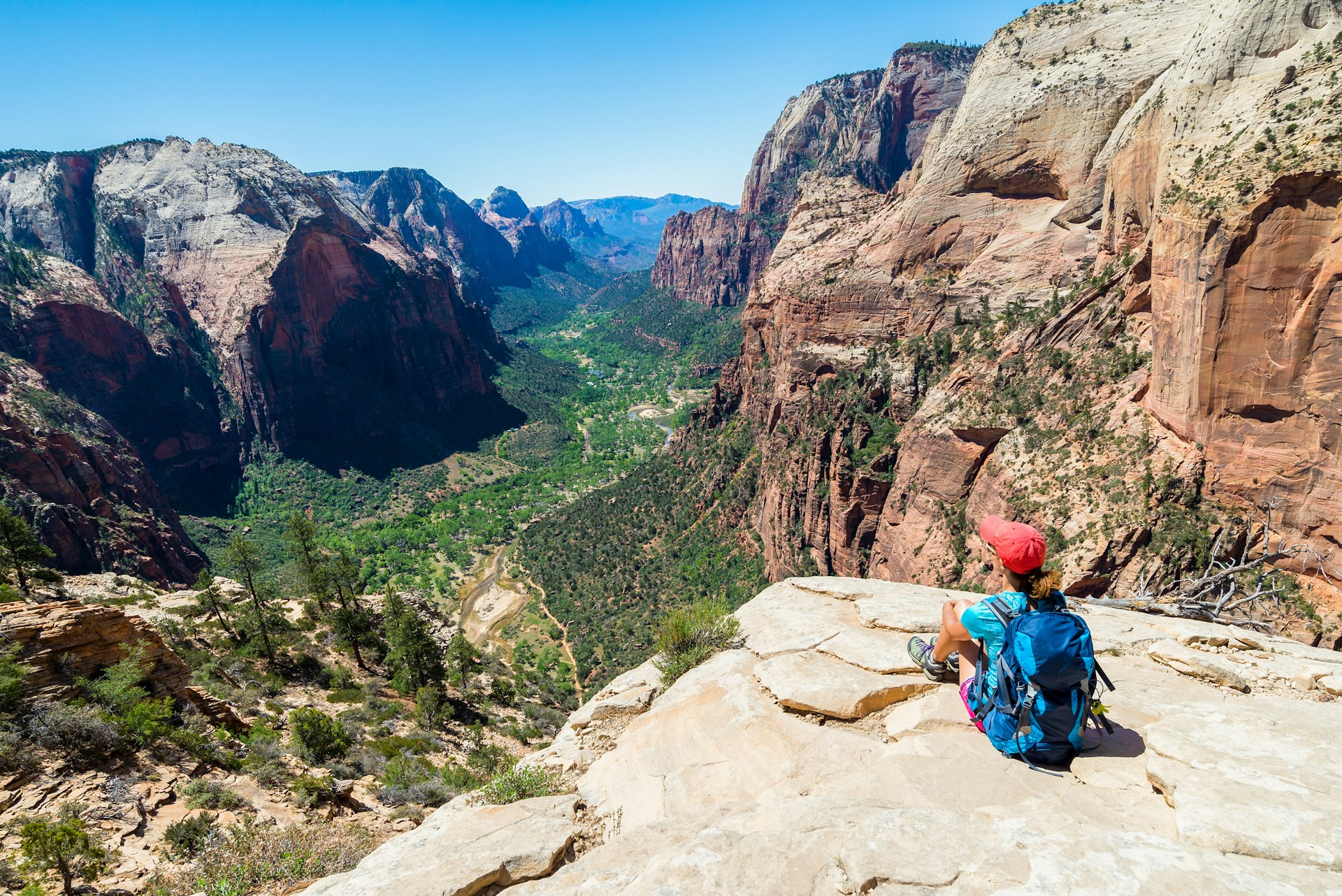 A female hiker sits, looking out over a deep canyon