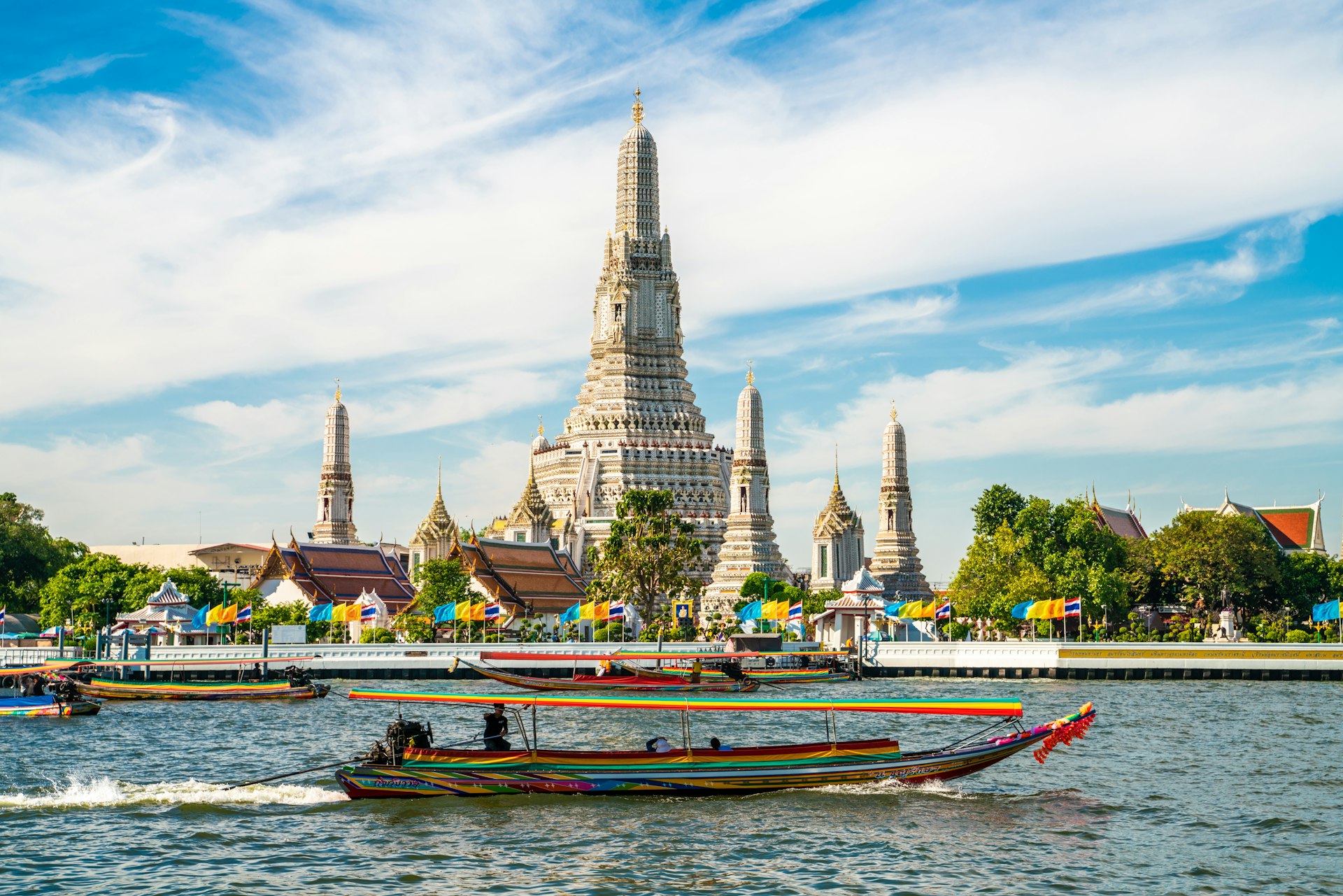 The temple of Wat Arun at dawn with a boat blue on a sunny day in Bangkok, Thailand.