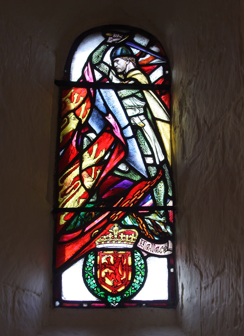 Chapel, Edinburgh Castle A stained glass window depicting a person in armour surrounded by colourful flags. There's a crest at the bottom