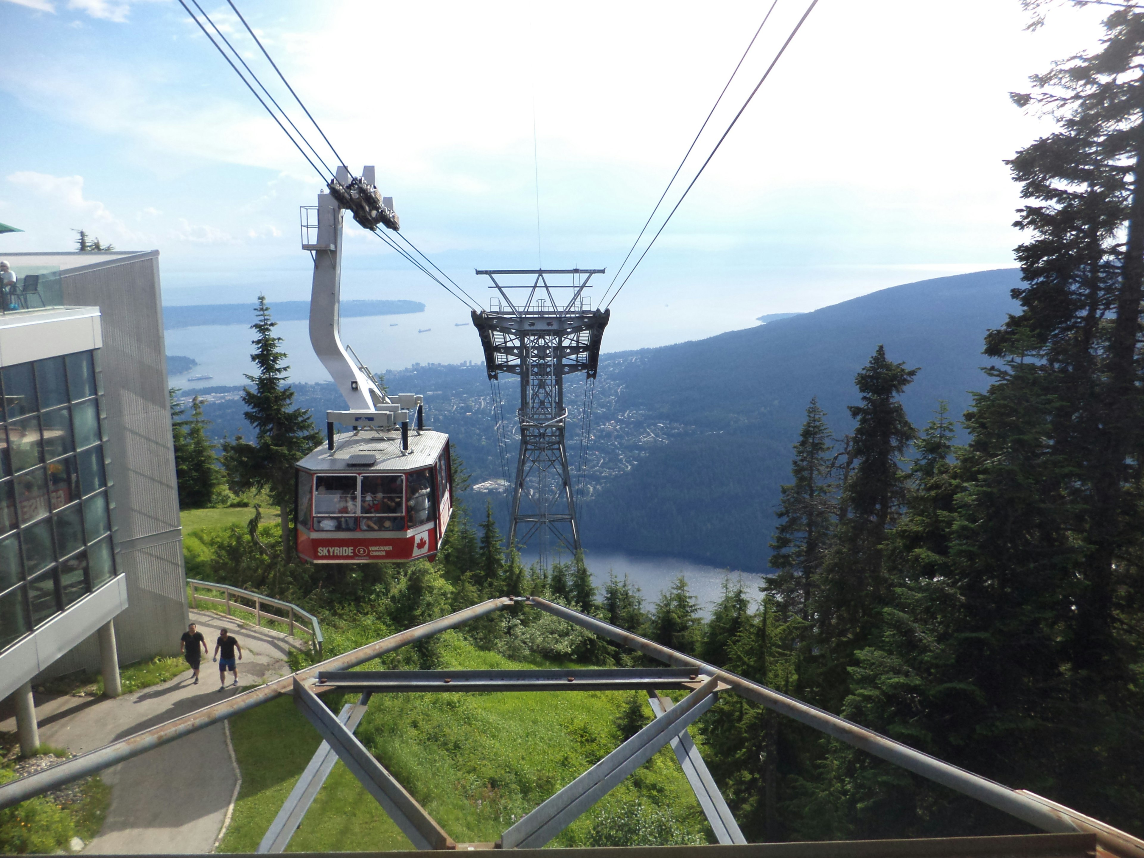 A cable car descends in front of beautiful mountain scenery.