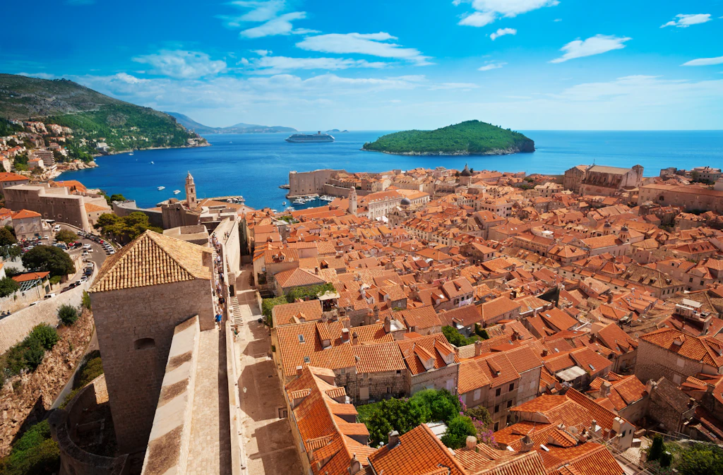 Dubrovnik old town A walkway along city walls with views over red rooftops to the sea in the distance