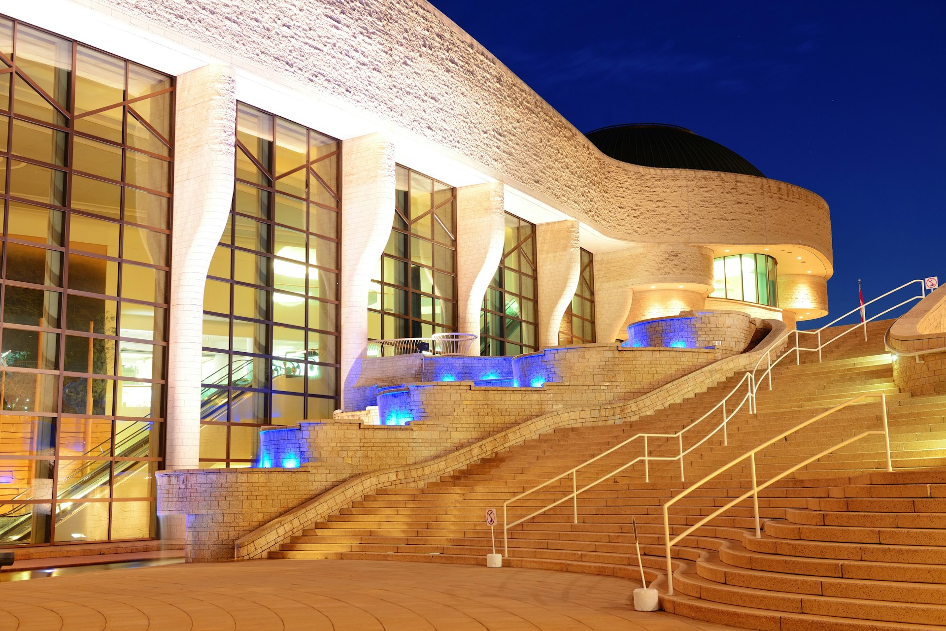 Steps in front of a brightly lit museum building at night. 