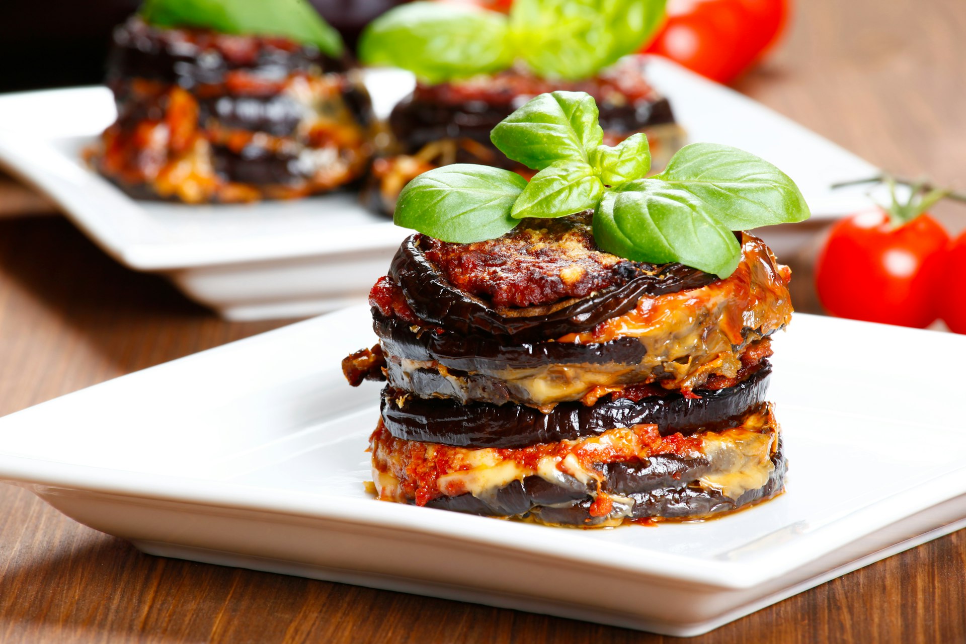 A stack of baked aubergine with oozing cheese between each slice