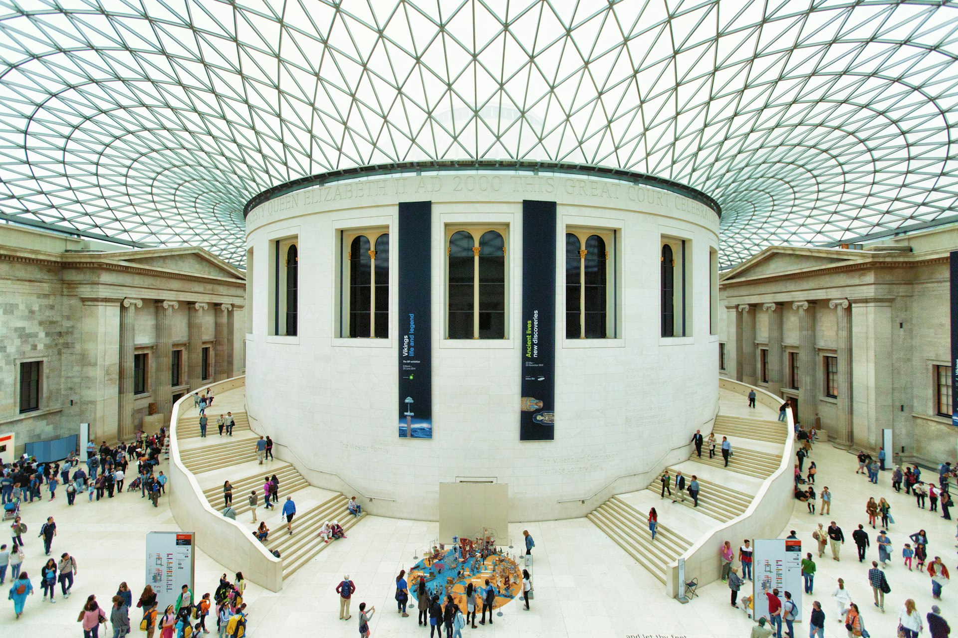 A huge space with a round central column, covered by a glass-and-steel roof. People are milling around the ground area and stairs