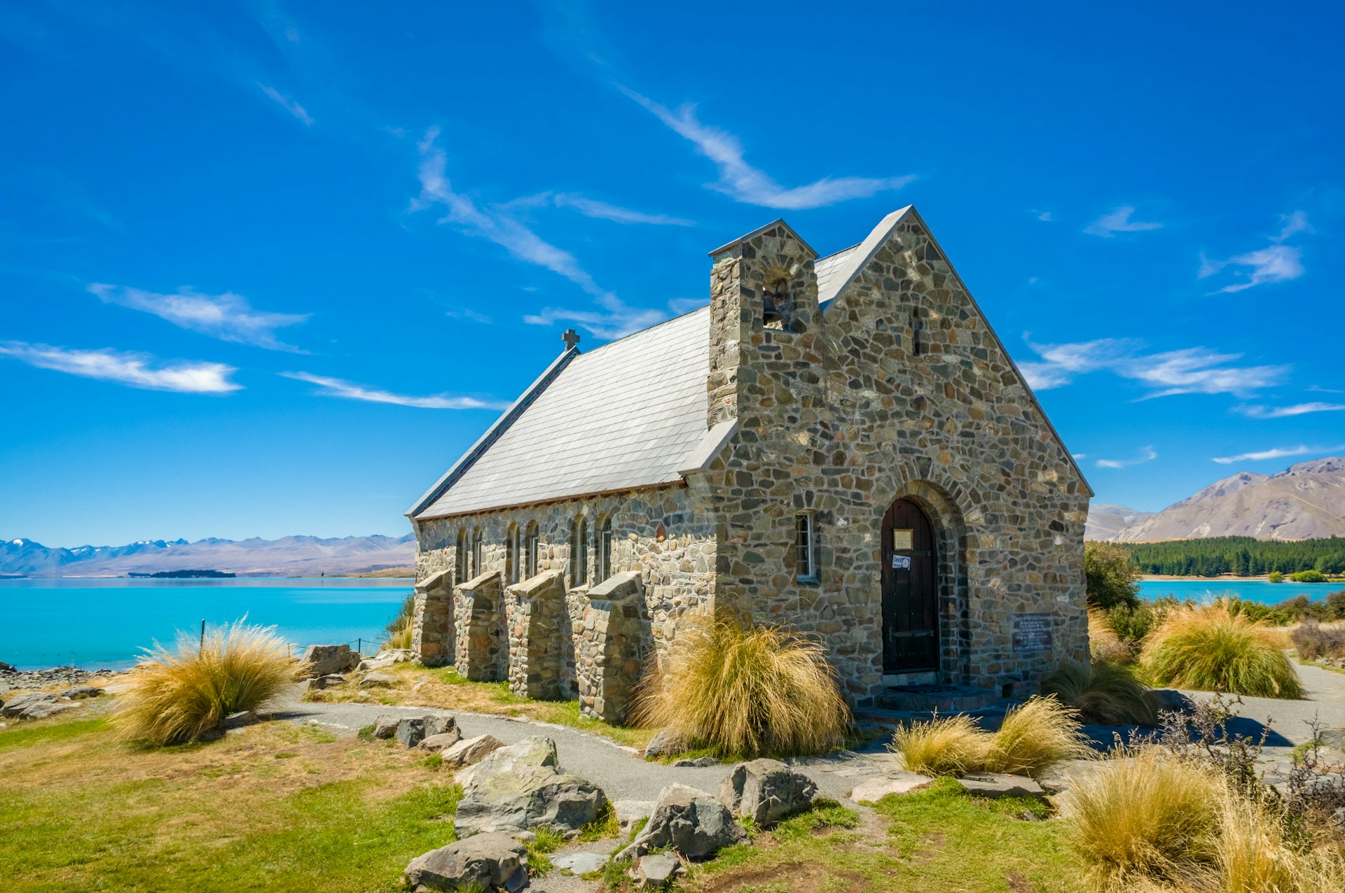 A small stone church built on the side of a turquoise lake