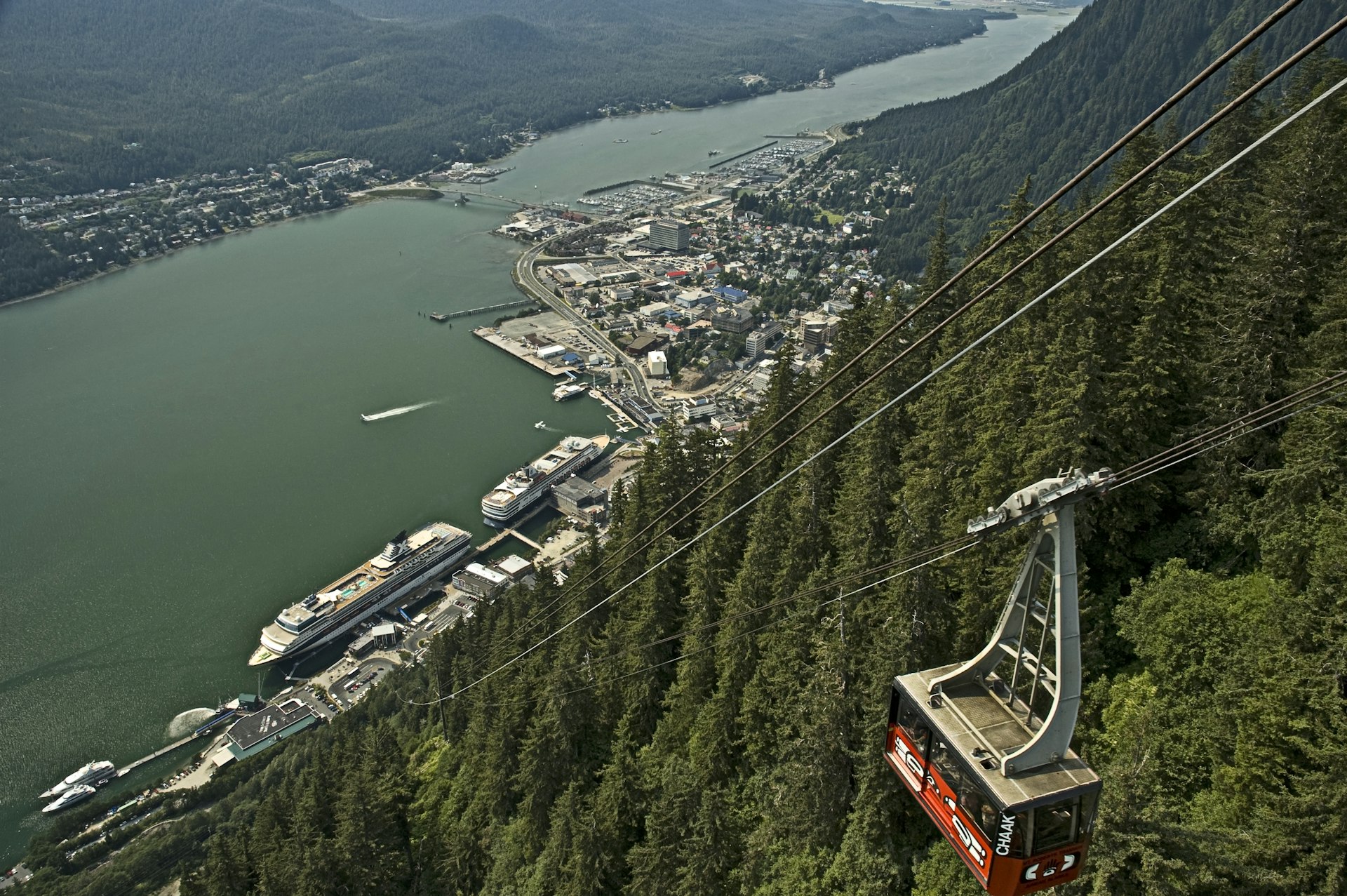 A suspended tram headed up a steep incline with trees in the background