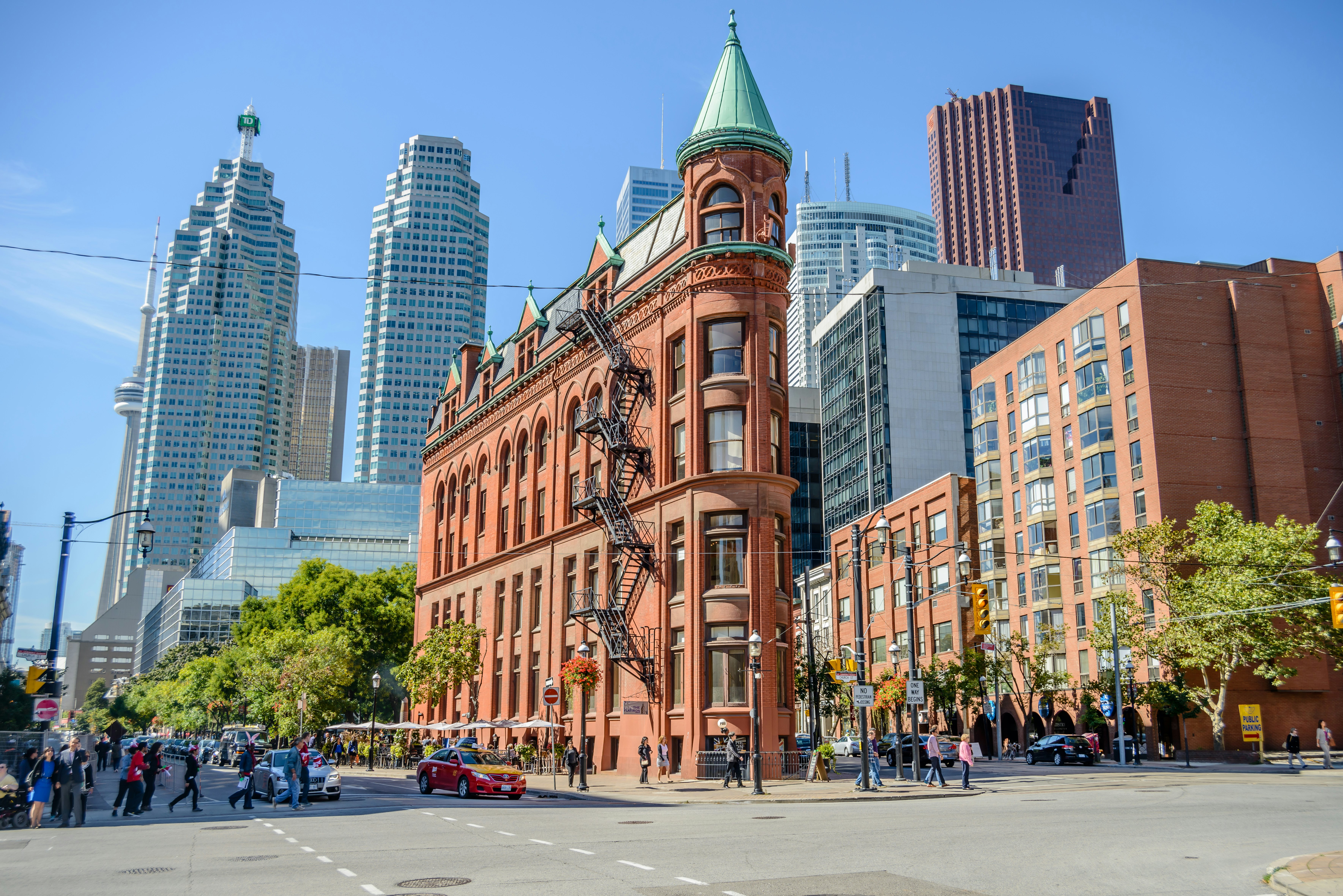 People walk in front of a red-brick bilding shaped like an iron and the intersection of streets