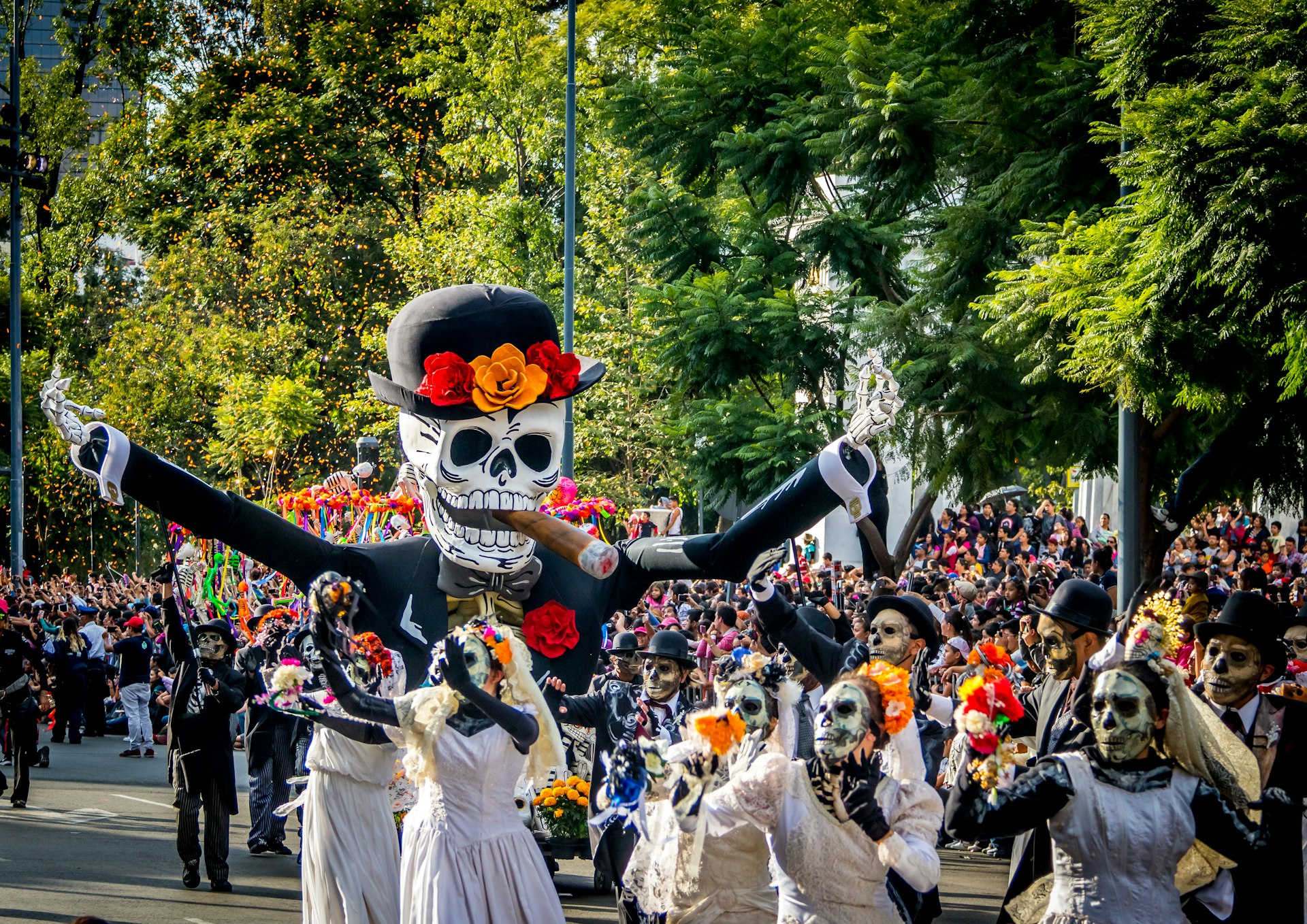 People dressed as la catrina calavera, marching in a Dia de Muertos parade