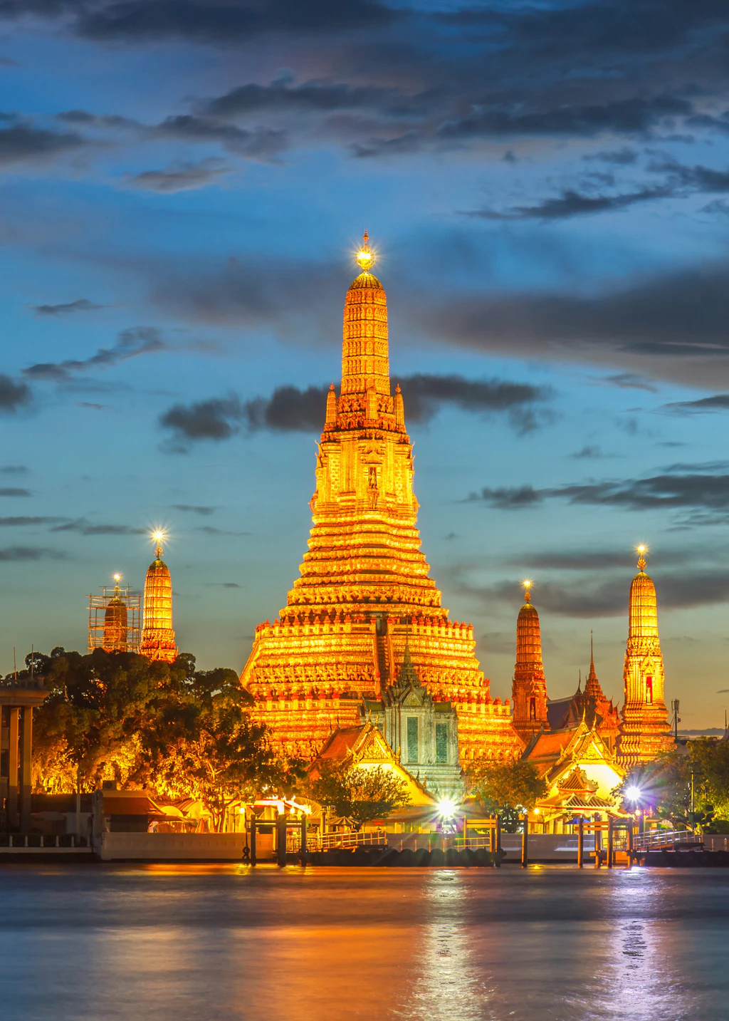 Wat Arun þrahng Wat Arun Buddhist temple glowing in golden light at twilight in Bangkok, Thailand.