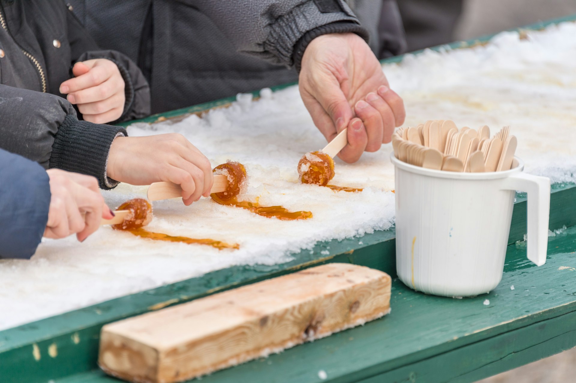 People putting maple taffy on snow at the sugar shack in Montreal. 