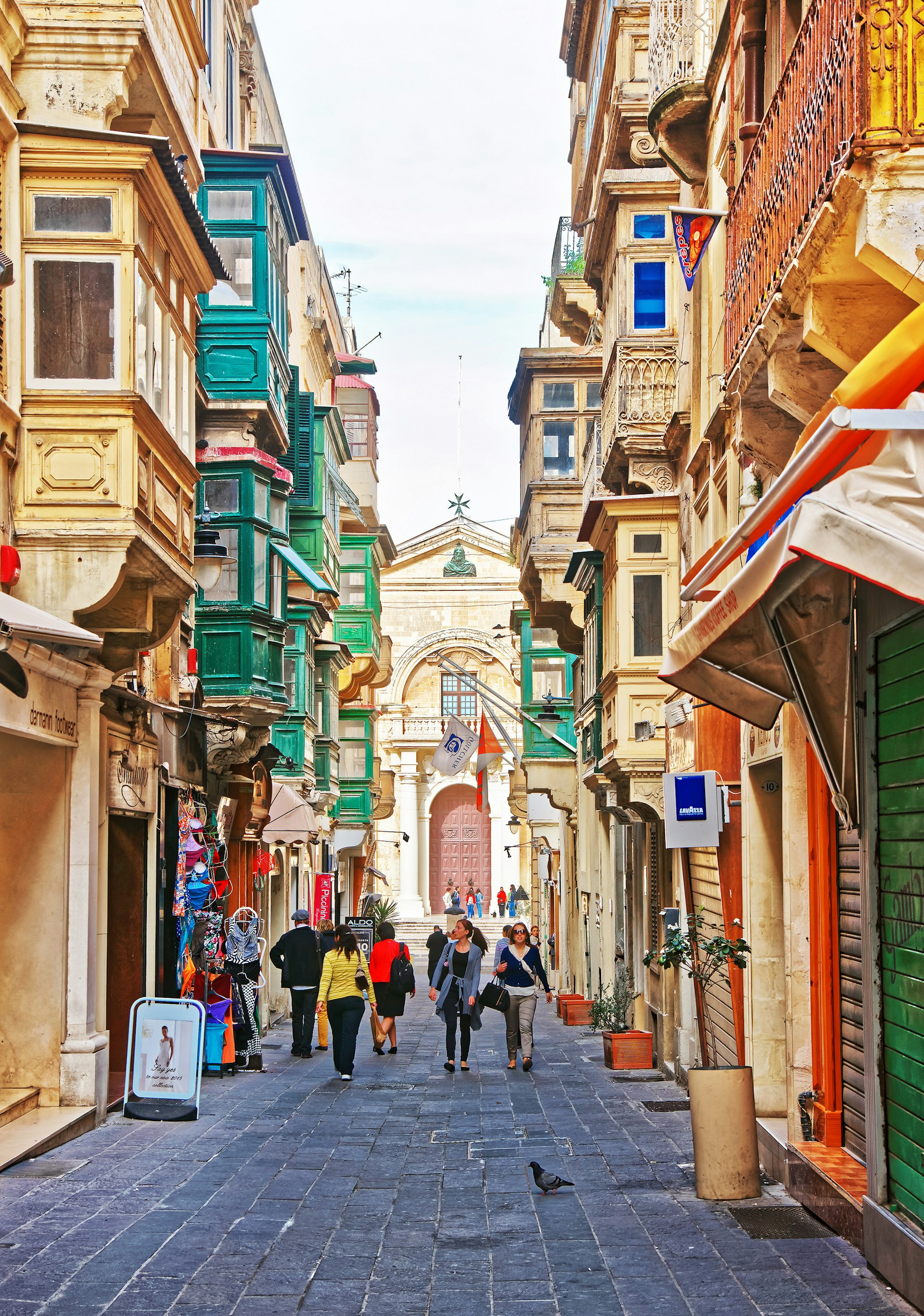 People in the street full of houses with traditional green balconies in Valletta old town
