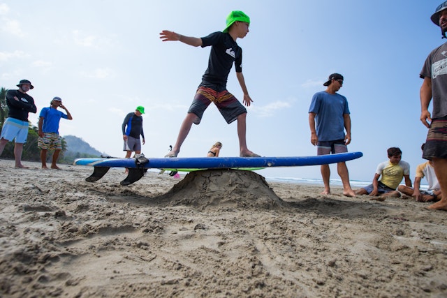 A child practices the basics of surfing on the beach