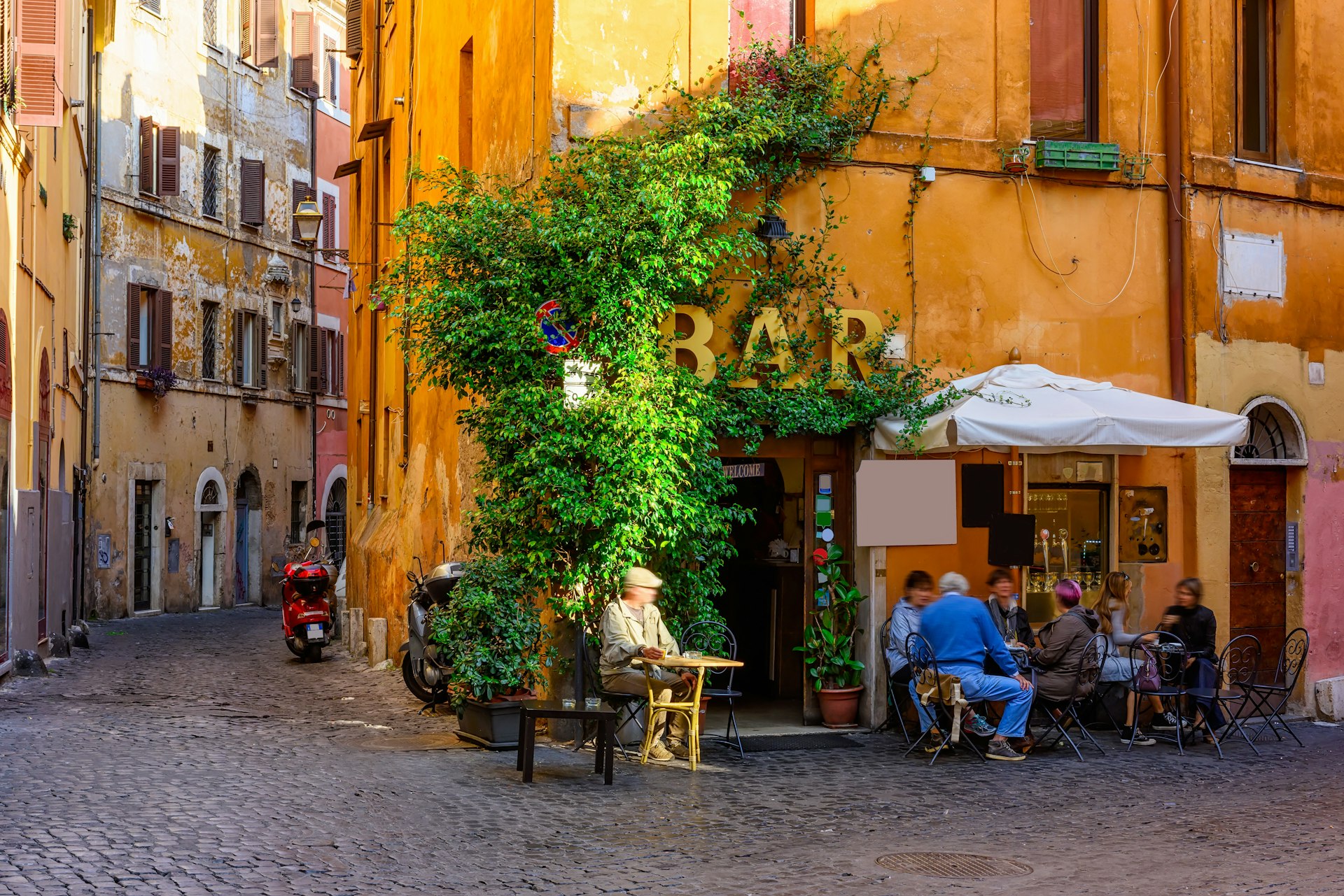 A quiet backstreet in Rome with people sat at tables of a corner bar