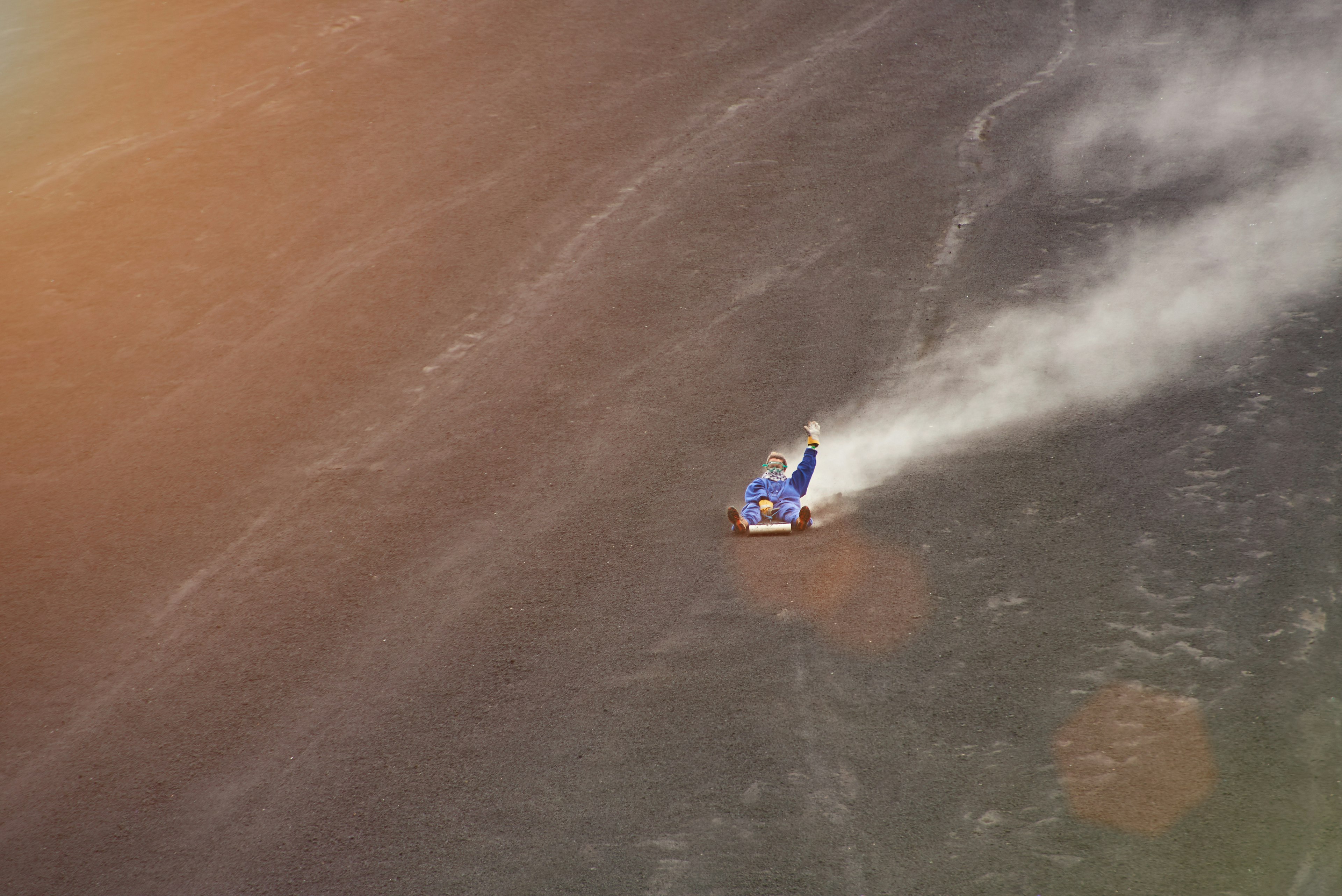 A man slides down the sooty side of a volcano at high speed in León, Nicaragua
