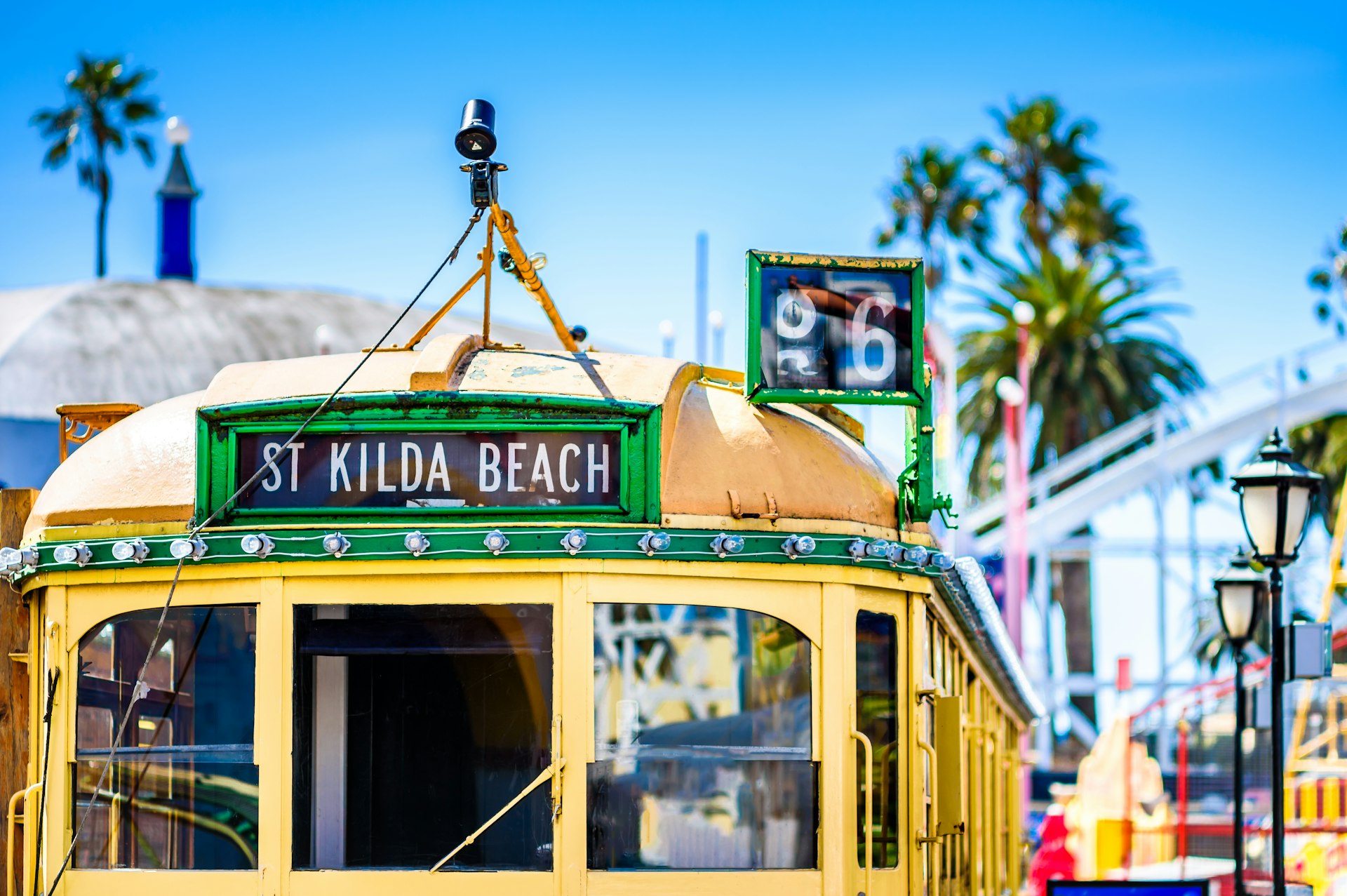 The top half of a yellow Melbourne tram, with a destination card that says 'St Kilda'. Behind the tram is a bright blue sky.