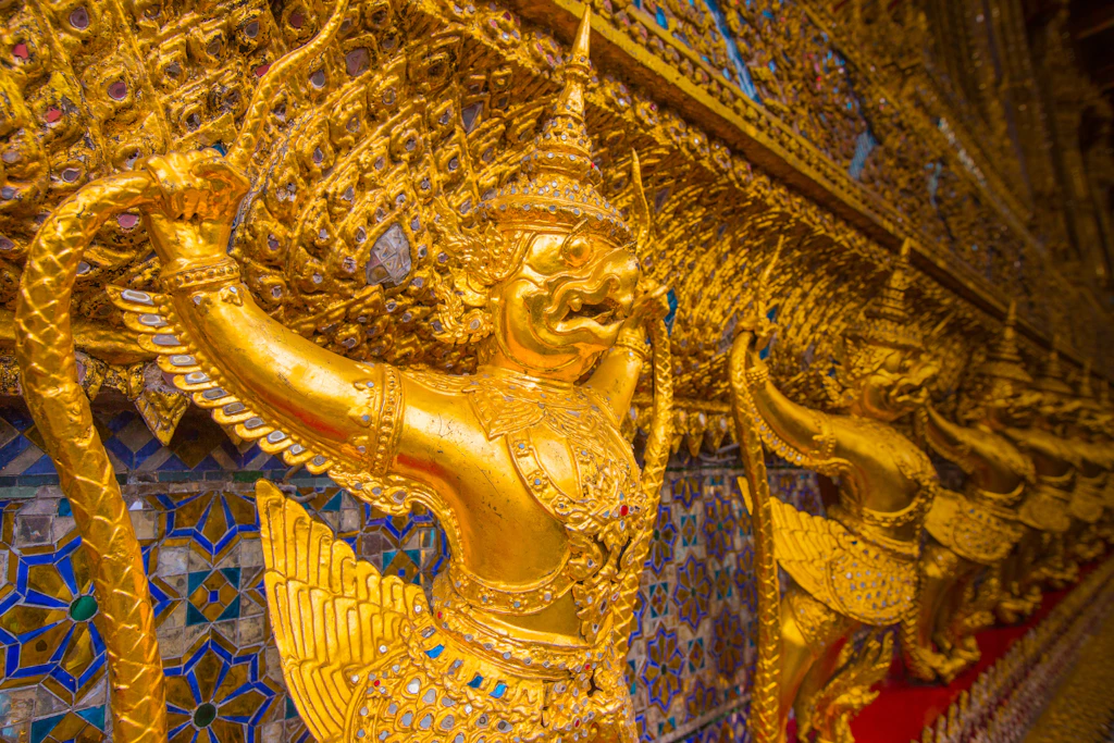 A row of ornate Buddhist carvings in gold inside Wat Phra Kaew, part of the Grand Palace in Bangkok.