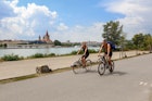 JULY 9, 2017: A young couple riding bicycles on Danube Island in the Donaustadt district. St. Francis of Assisi Church is in the background.