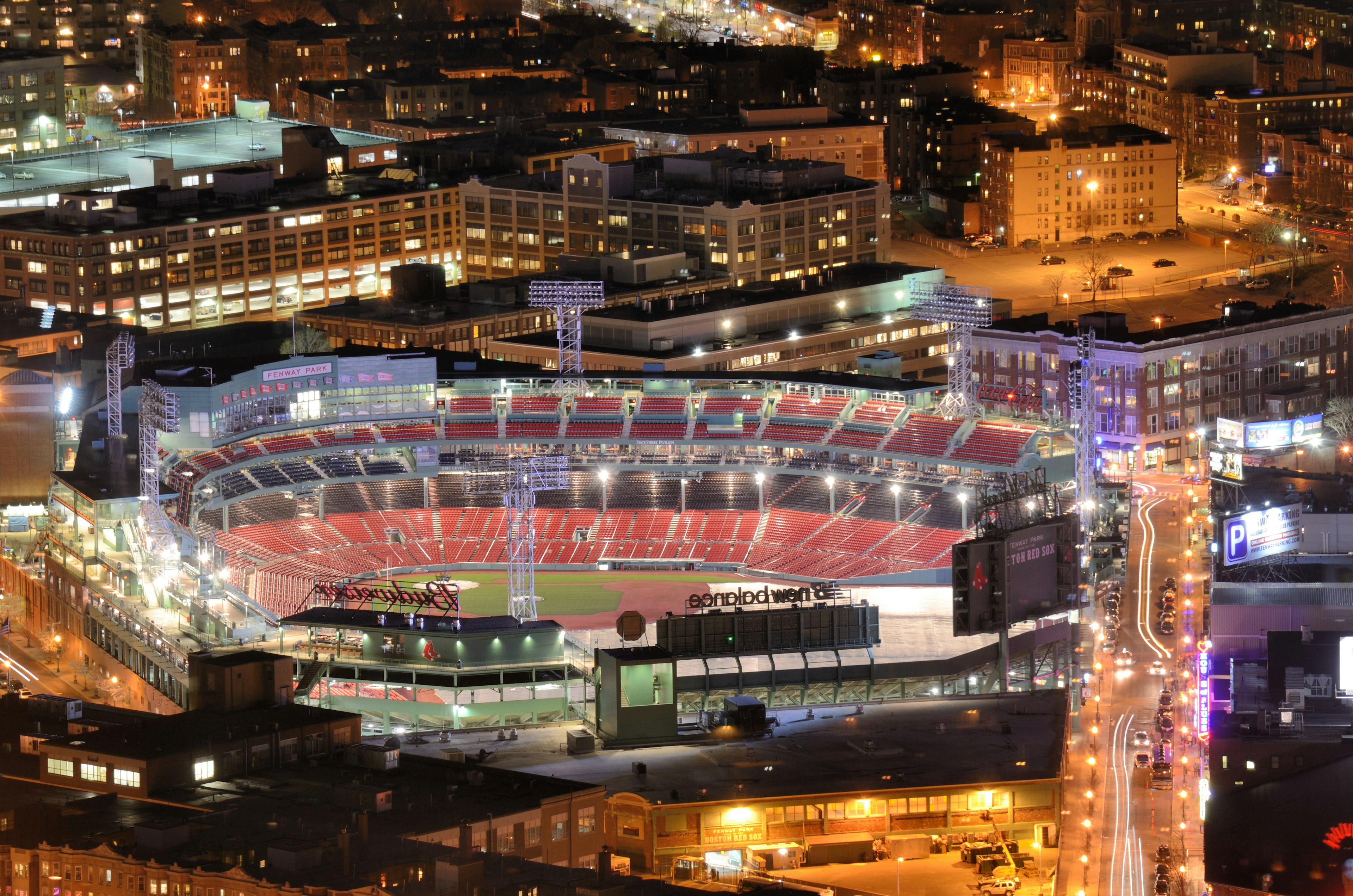 An aerial shot of a lit-up sports stadium in a built-up area