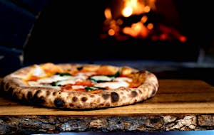 Rustic wooden table with pizza Margarita with fire in the back