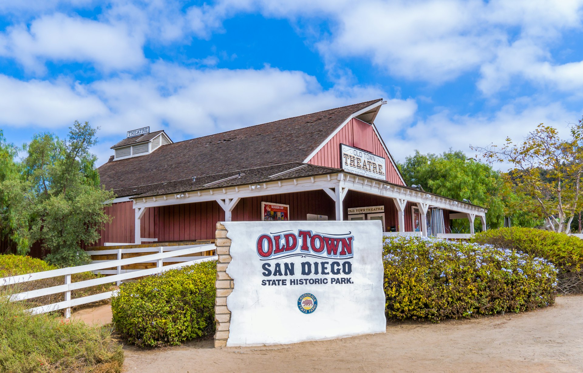 A sign reading "Old Town San Diego State Historic Park" stands in front of an old-fashioned wooden building with a pointed roof
