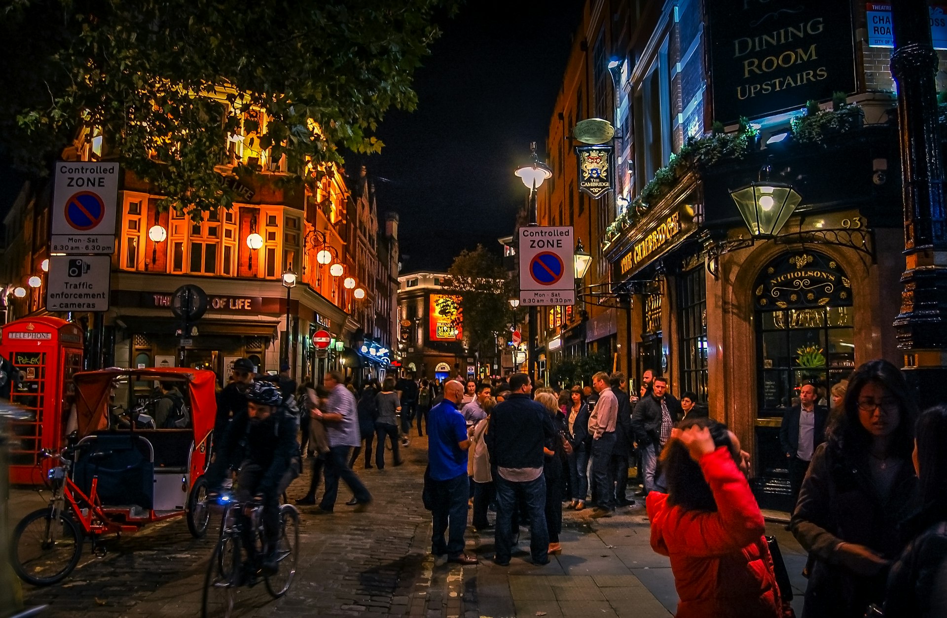 People standing on the street outside bars and pubs in Soho, London  