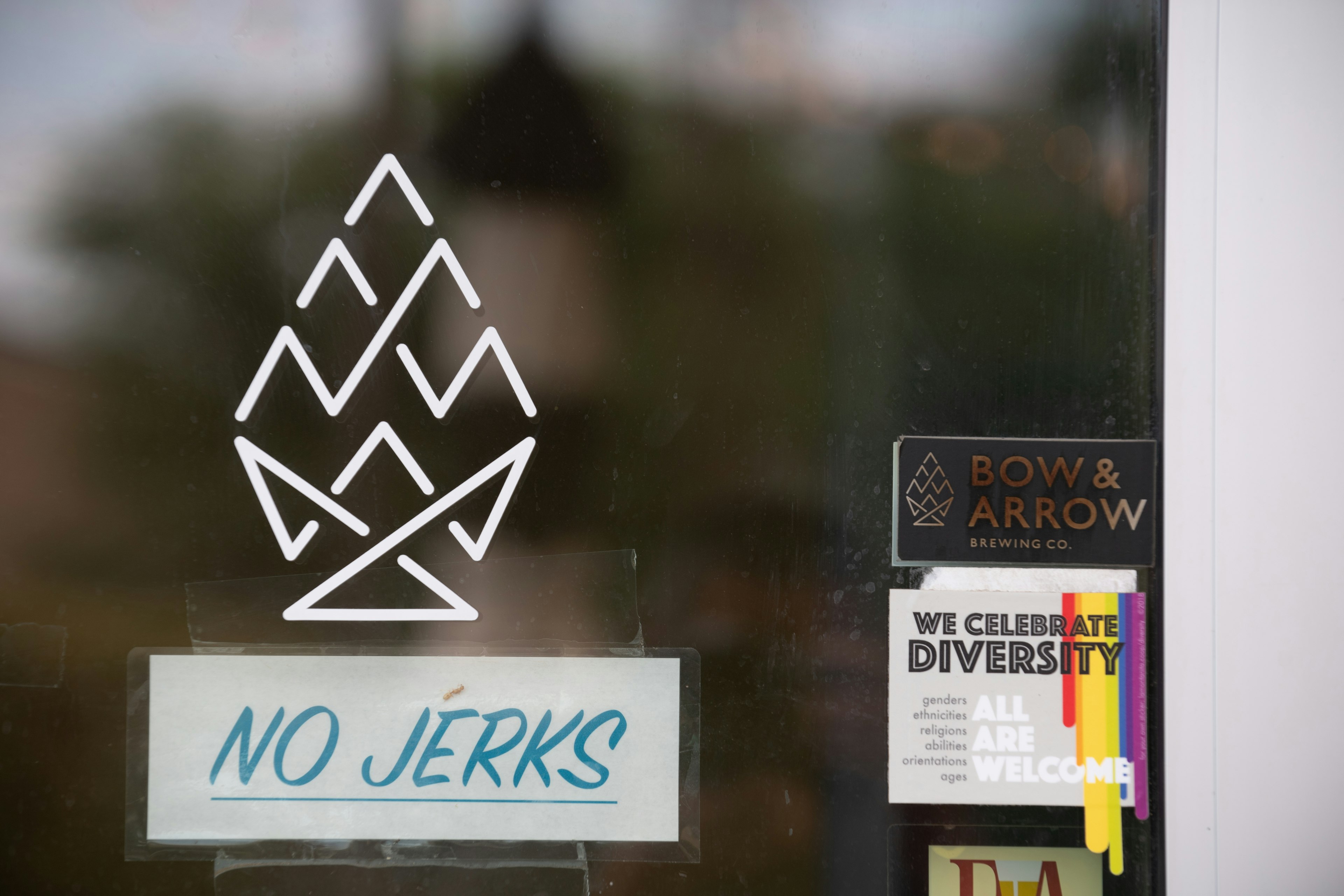 An exterior view shows a ‘No Jerks’ sign taped to the front door of the Bow and Arrow Brewery on in Albuquerque, New Mexico.