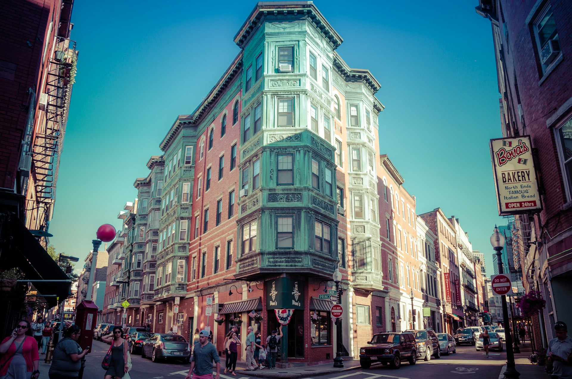 A shot of a pastel-colored corner building rising above a busy street 