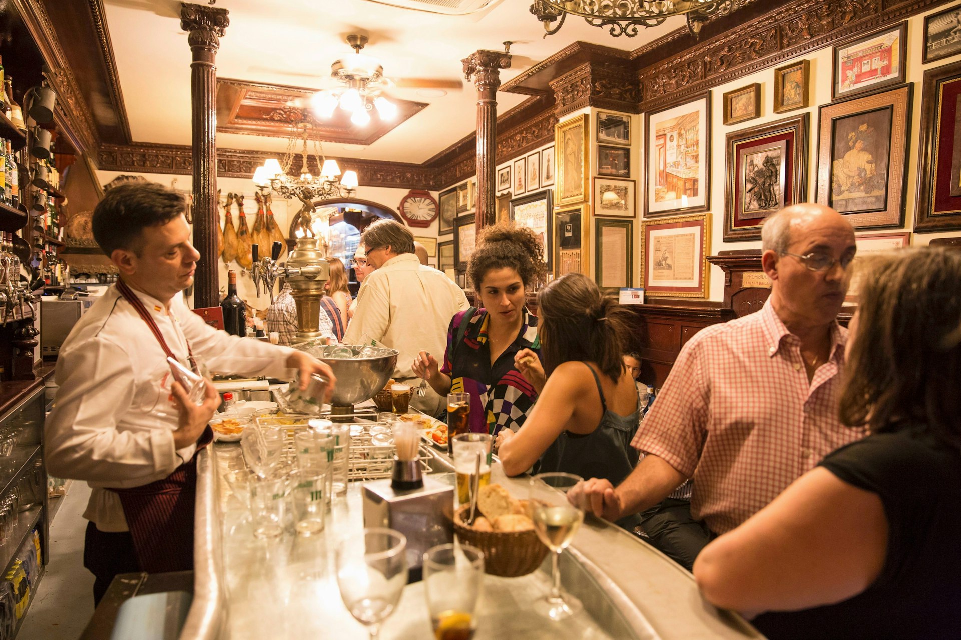 Guests chatting at the bar in 'Casa Alberto' tapas bar in Madrid, Spain