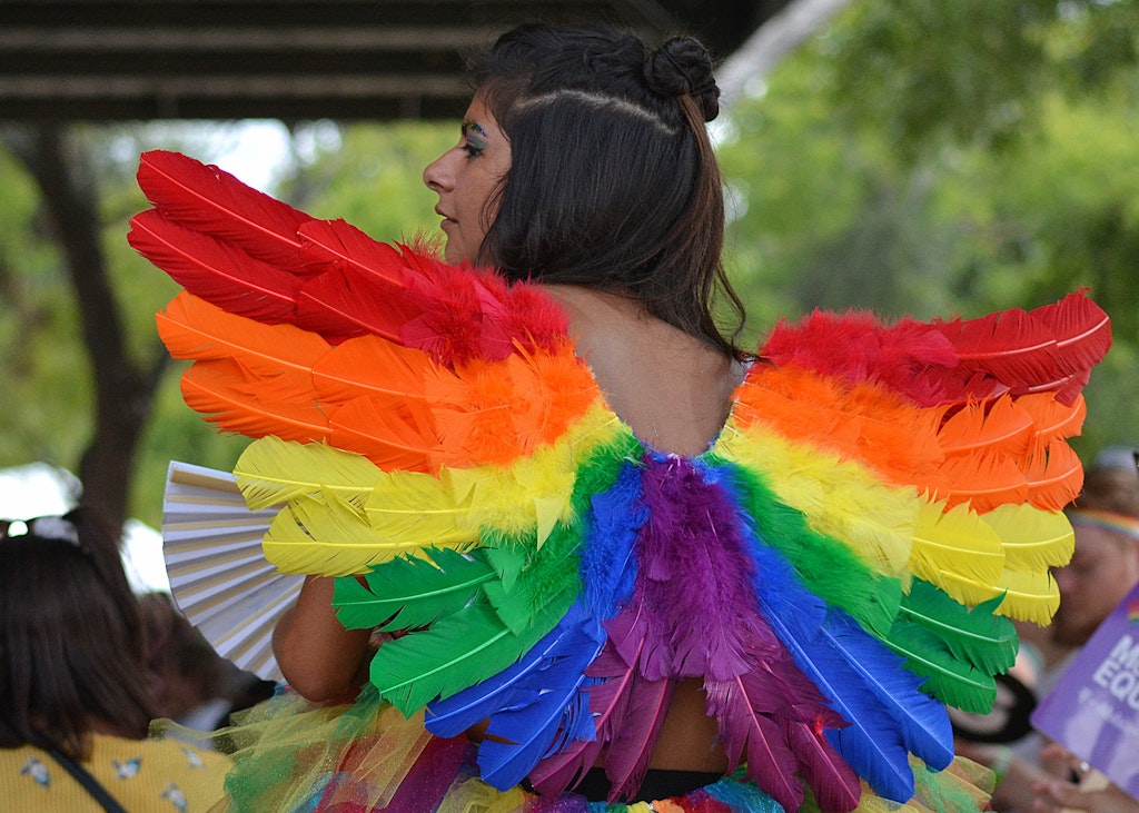 A woman in rainbow colored angel wings participating in the Austin pride festival