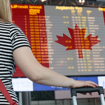 Woman looks at the scoreboard at the airport. Select a country Canada for travel or migration.