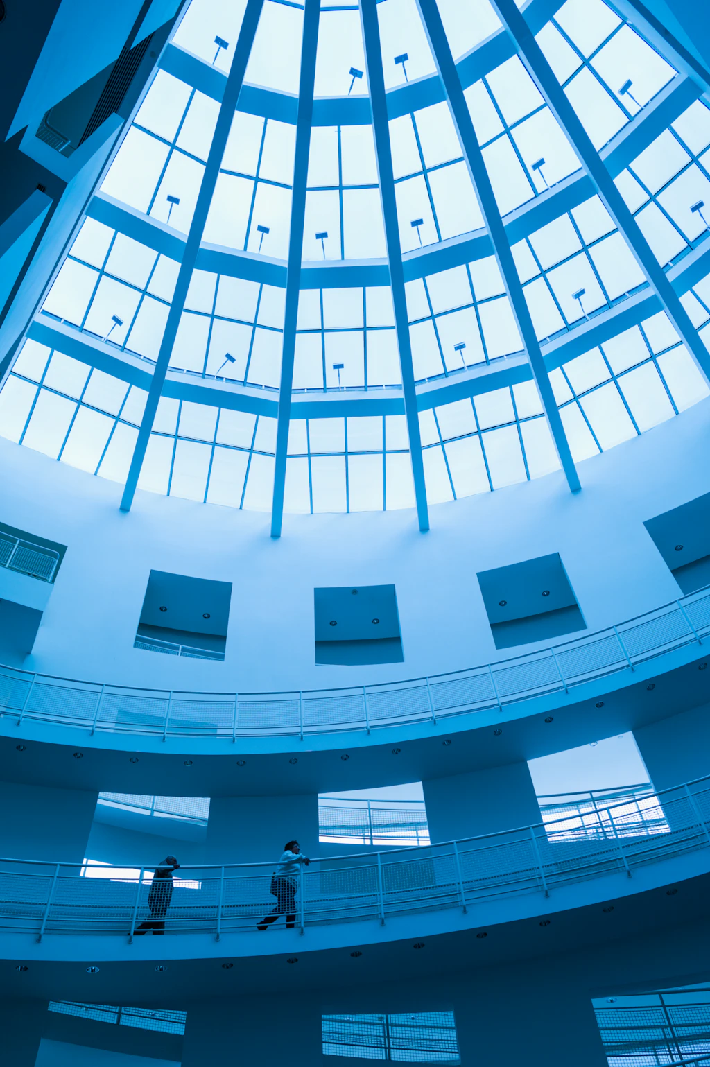 A light-filled atrium with white walls and ramps running up the side of it