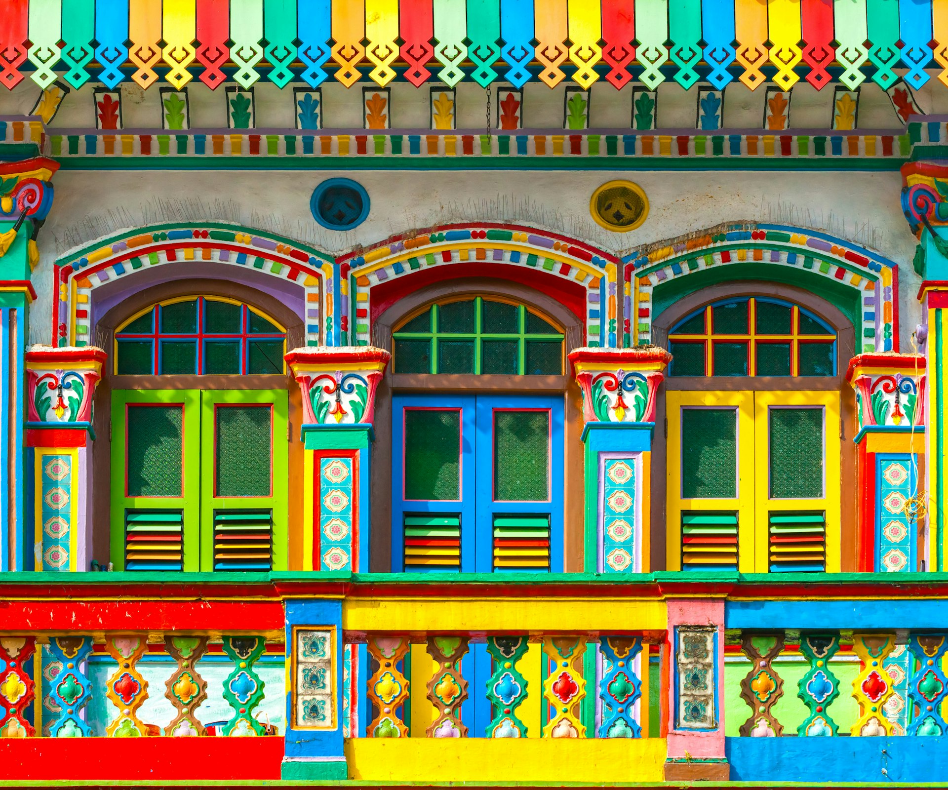 Three colorful Little India shopfronts painted in blues, greens, yellows and reds in Singapore 