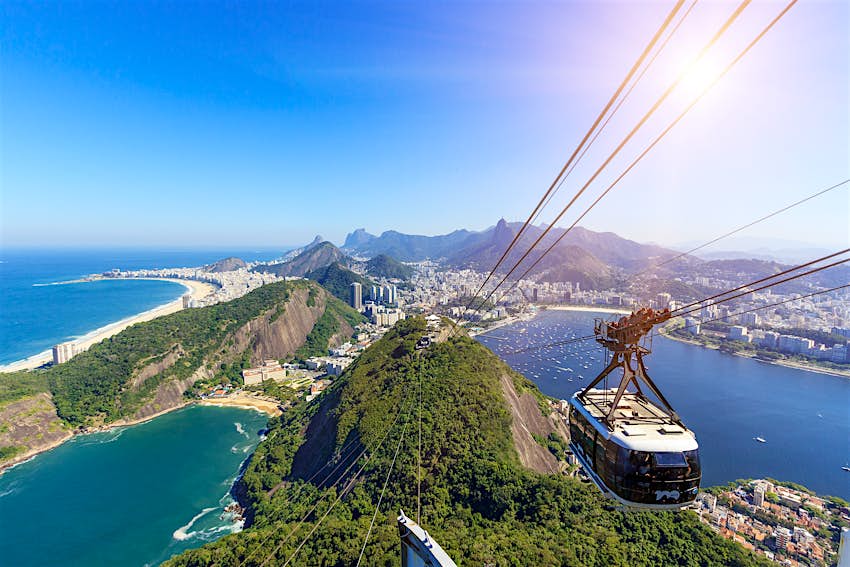 A vista é do Pão de Açúcar, com vista para o teleférico que vai para o Rio de Janeiro no Brasil com o oceano azul brilhante por baixo. 