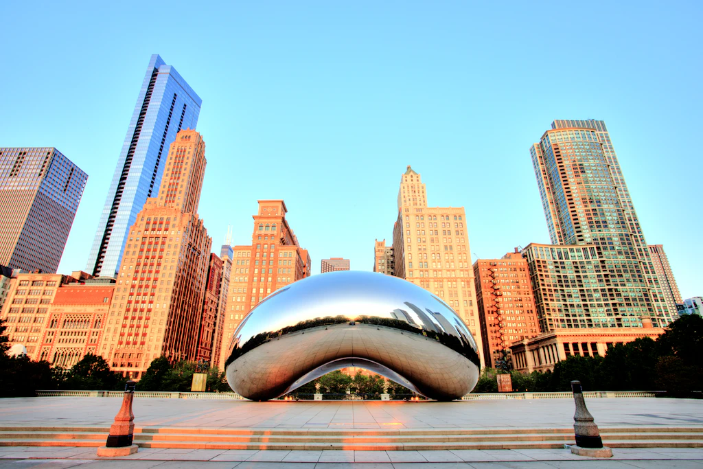 Cloud Gate in Millennium Park at Sunrise, Chicago A large freestanding metal sculpture with smooth sides in the middle of a public square