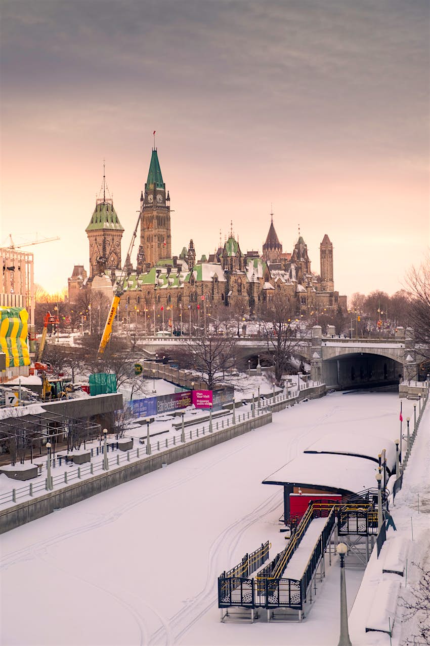 A frozen Rideau Canal cuts along past the Parliament building in Ottawa, Canada at sunset.