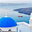 Blue dome church of Santorini island, Greece, Fira village. Island and moored red ferry in background, Morning scenery.