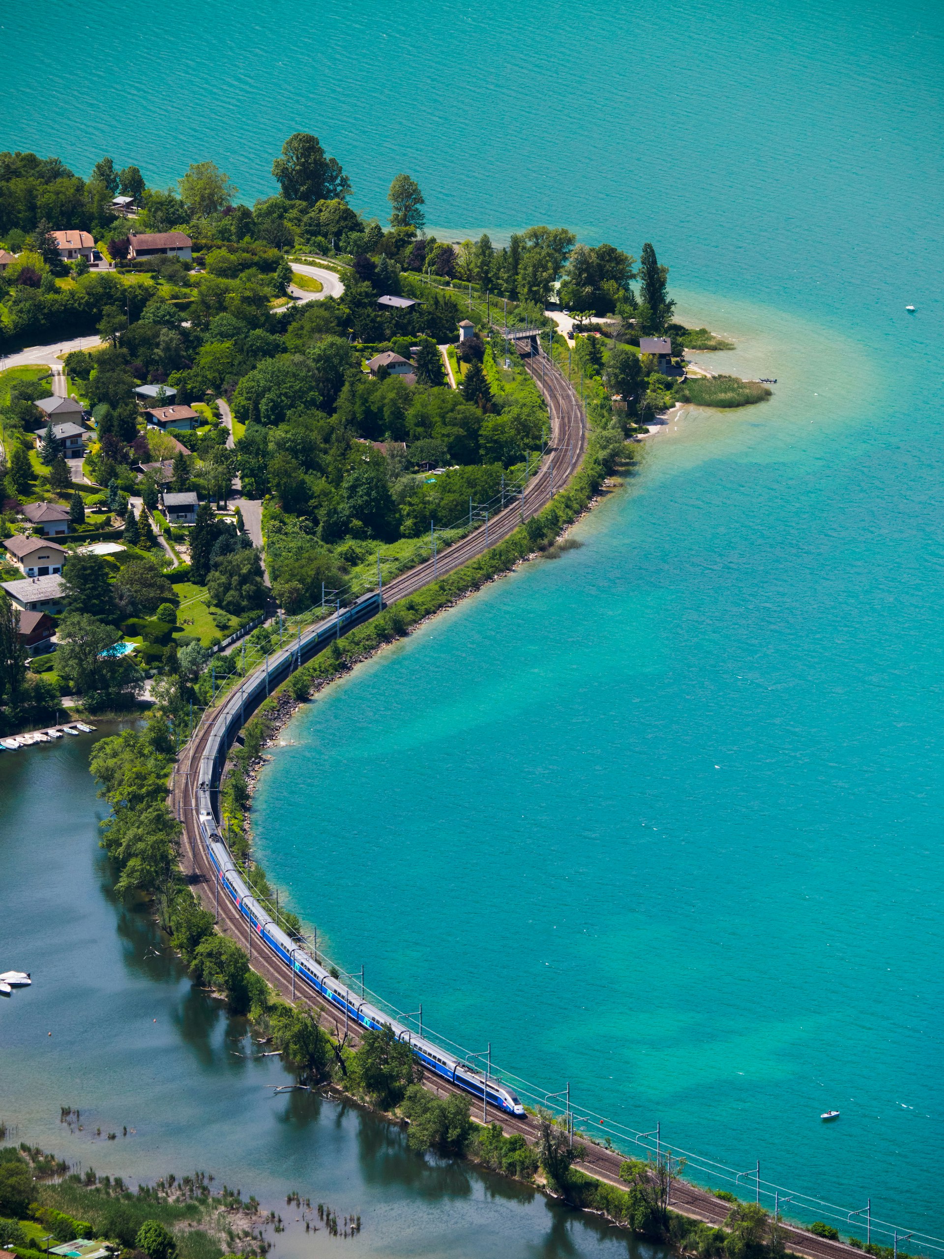 An aerial shot of a trainline with a bridge over a body of water