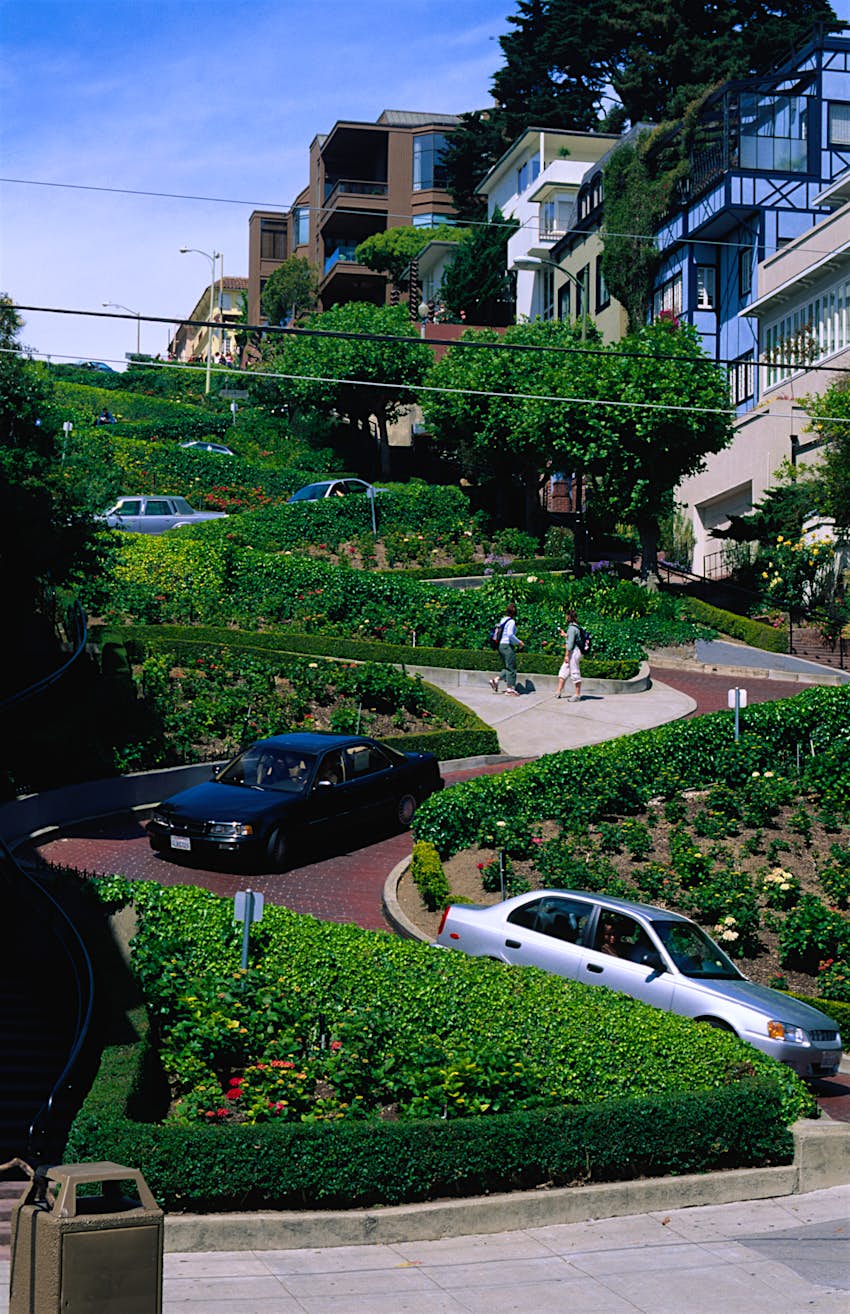 Traffic curls its way down Lombard Street in San Francisco which snakes around green shrubbery. 